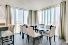 a dining room table with white chairs and curtains