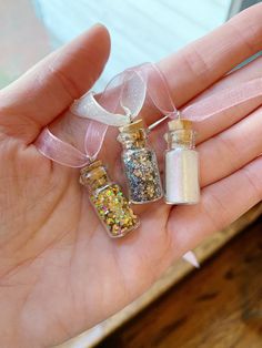 three tiny bottles with glitter inside are held in someone's hand