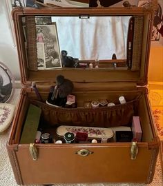 an open suitcase sitting on top of a bed next to a mirror and other items