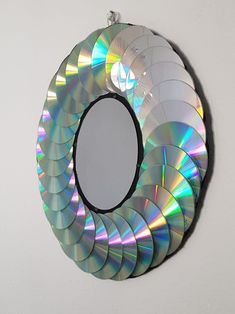 a circular mirror hanging on the wall with cd discs in it's center piece