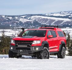 a red pick up truck parked in the snow