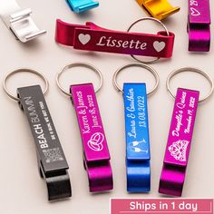 four different colored metal key chains with name tags attached to them, and one has a bottle opener in the shape of a heart