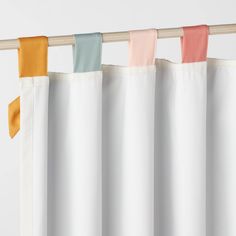 four different colored curtains hanging on a wooden rod