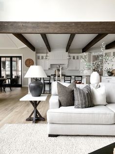 a living room filled with furniture next to a dining room table and two lamps on either side of the couch