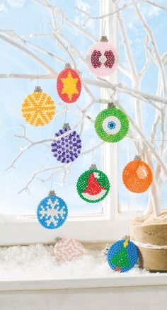 christmas ornaments hanging from a window sill in front of a snow - covered tree