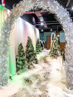 an indoor christmas display with fake trees and snow on the ground in front of it