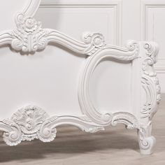 an ornate white bed frame against a wall