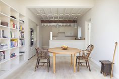 an open kitchen and dining room area with wooden table, chairs and bookshelves