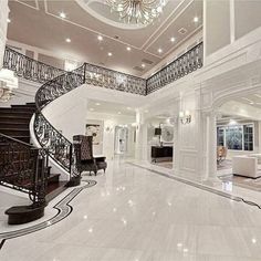 a large foyer with stairs and chandelier in the middle of it, surrounded by white marble flooring