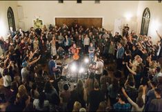 a large group of people standing in front of a stage with musical instruments and microphones