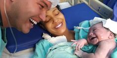 a man and woman smile as they hold a baby in a hospital bed with an oxygen tube