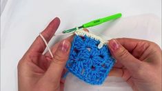 two hands are crocheting together to make a square