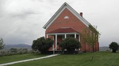 a small red brick house sitting on top of a lush green field