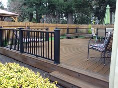 a deck with chairs and umbrellas on it next to a fenced in area