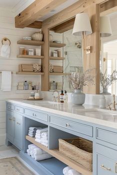 a large bathroom with blue cabinets and white towels on the counter top, along with shelves filled with toiletries