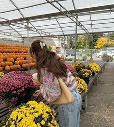 a woman looking at flowers in a greenhouse