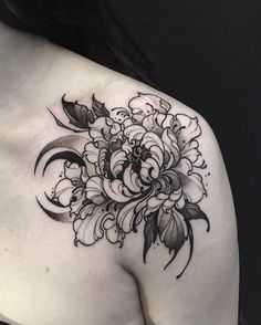 a black and white flower tattoo on the back of a woman's shoulder