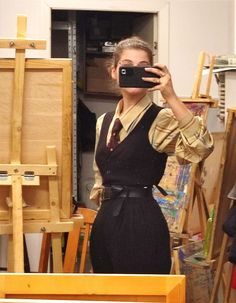 a woman taking a selfie in front of an easel