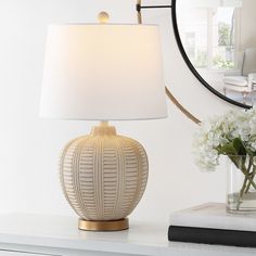 a white lamp sitting on top of a table next to a vase filled with flowers