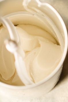 a white cup filled with cream sitting on top of a table