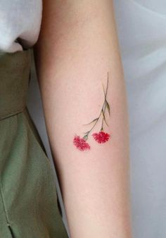 a small red flower tattoo on the arm