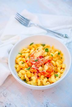 a white bowl filled with macaroni and cheese on top of a marble table