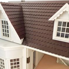 a doll house with brown roof and white trim