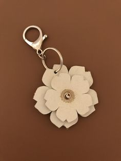 a white flower keychain sitting on top of a brown surface