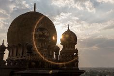 the sun shines brightly behind two domes on top of a building