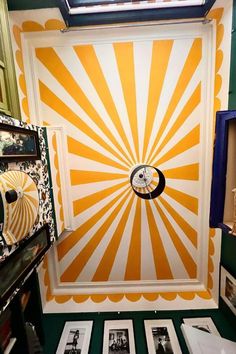 a room that has some pictures on the wall and an orange sunburst painted on the wall