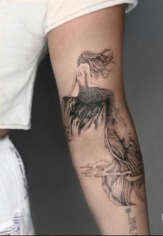 a woman's arm with a mermaid tattoo on the left side of her body