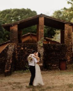 a bride and groom standing in front of an old building with stone pillars on the side