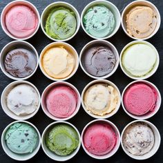 an array of different colored ice creams in bowls on a blue background with copy space