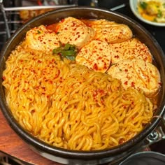 a pan filled with noodles and tofu on top of a table