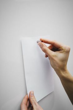 two hands holding up a piece of white paper