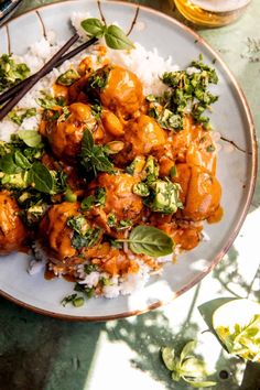 a white plate topped with chicken and broccoli covered in sauce next to rice