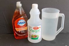 a bottle of vinegar next to a jug of water and a glass container with liquid