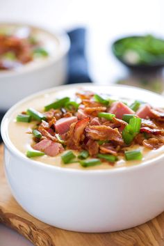 two bowls filled with soup on top of a wooden cutting board