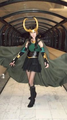 a woman dressed as loki in a hallway with horns on her head and cape around her neck