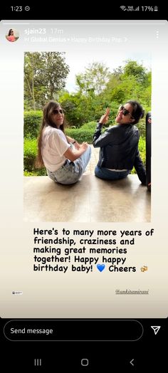 two people sitting on the ground with a birthday message in front of them and one person holding