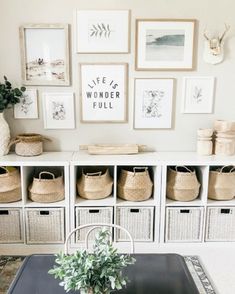 a dining room table with baskets on it and pictures hanging above the table in front of it