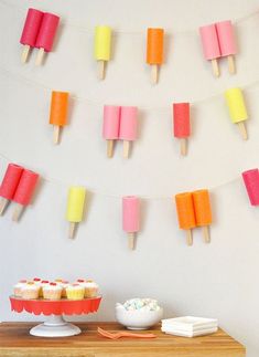 some cupcakes and marshmallows are on a table with paper streamers