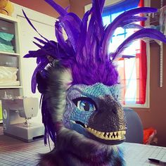 a dinosaur mask with purple feathers on it's head sitting on top of a table