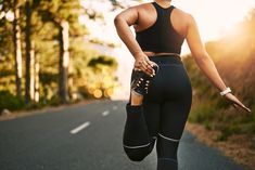 a woman is running down the road in her sports bra and leggings