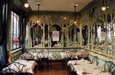 the interior of a restaurant with green walls and tables set up for two people to eat