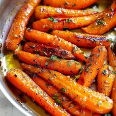 cooked carrots with herbs and seasoning in a white serving dish on a table