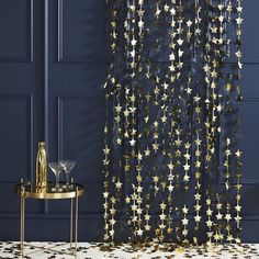 a room with blue walls and gold stars on the curtain, next to a side table