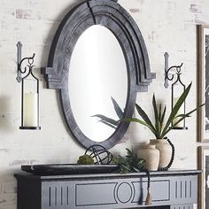 a living room with a fireplace, mirror and plant on the mantle in front of it