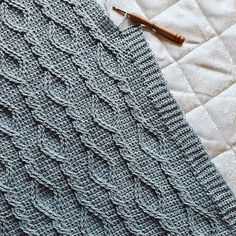 a crocheted blanket laying on top of a bed next to a wooden pen