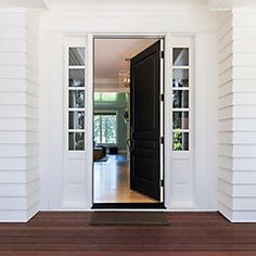 an open door to a white house with wood flooring